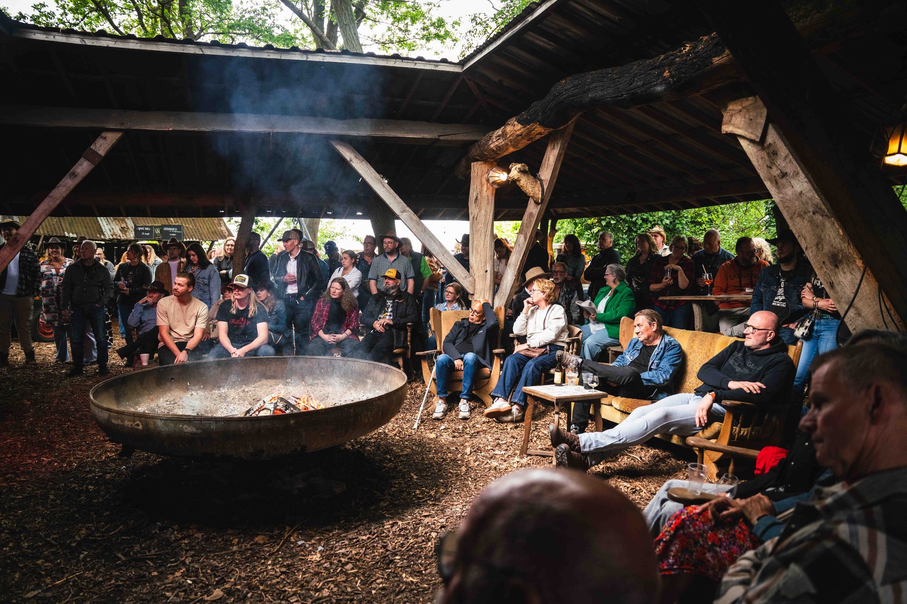 Publiek rond het kampvuur bij schemer