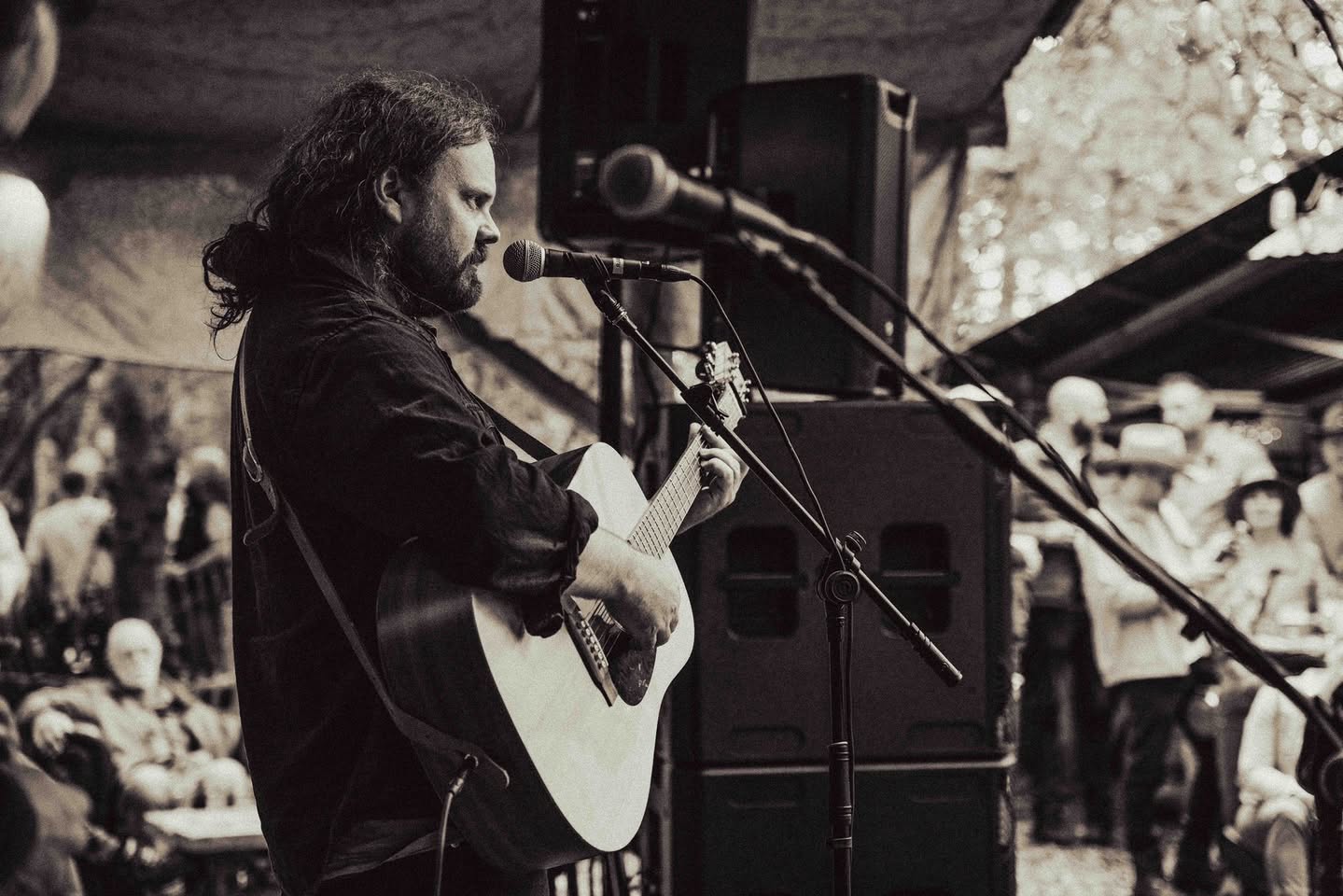 Singer-songwriter met akoestische gitaar op het podium onder de tent